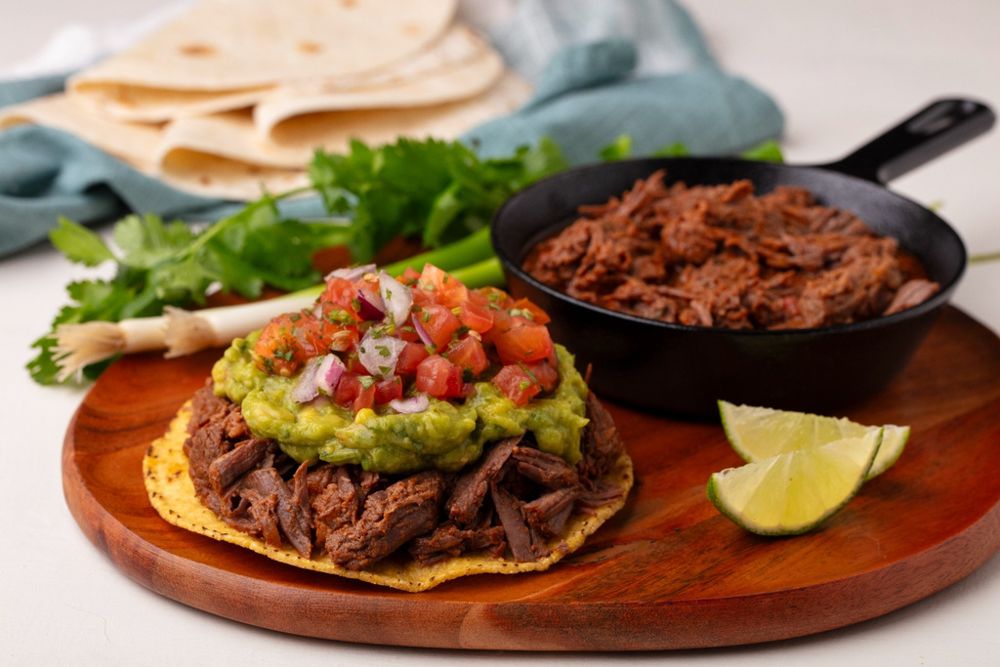 Slow-cooked shredded beef birria on a tostada